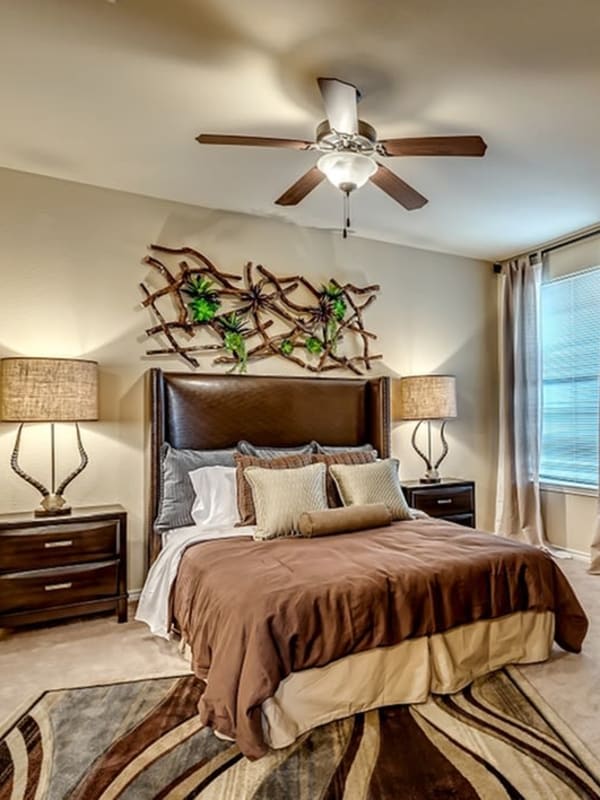 Model master bedroom with plush carpeting and a ceiling fan at Chateau Mirage Apartment Homes in Lafayette, Louisiana