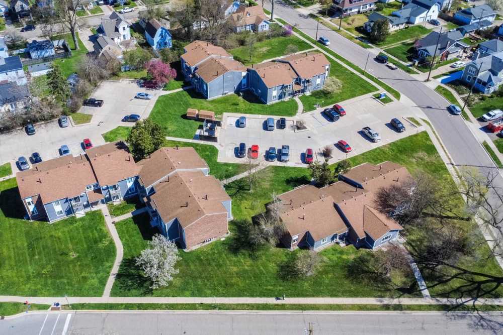 Drone view of buildings with car parking at Milan Village in Milan. MI