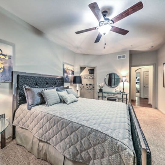 Bed and nightstand in a model home's bedroom at Grand Villas Apartments in Katy, Texas