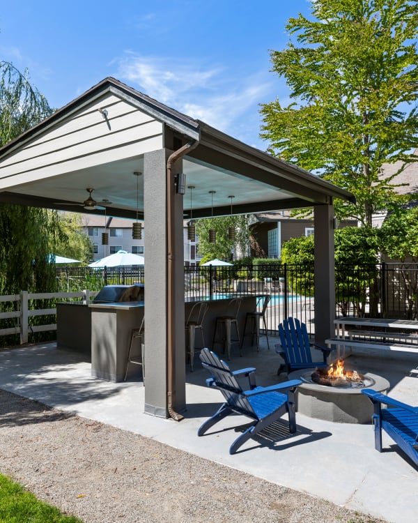 Covered outdoor BBQ and fire-pit lounge at Olin Fields Apartments in Everett