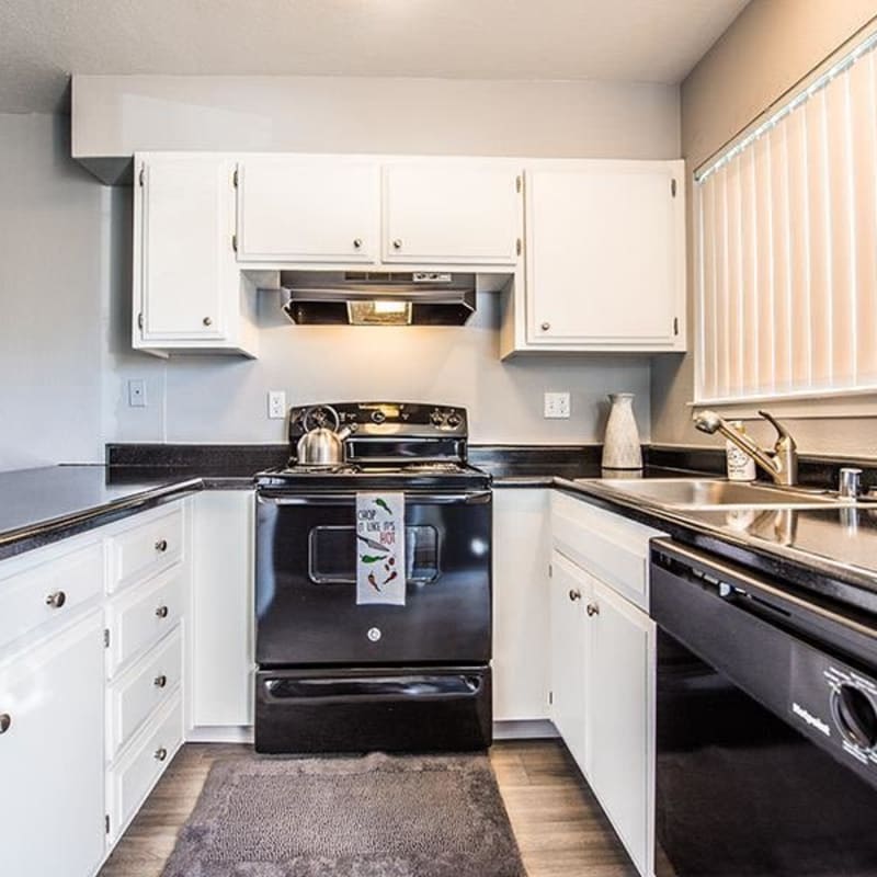 Kitchen with plank flooring and black appliances at The Eleven Hundred in Sacramento, California