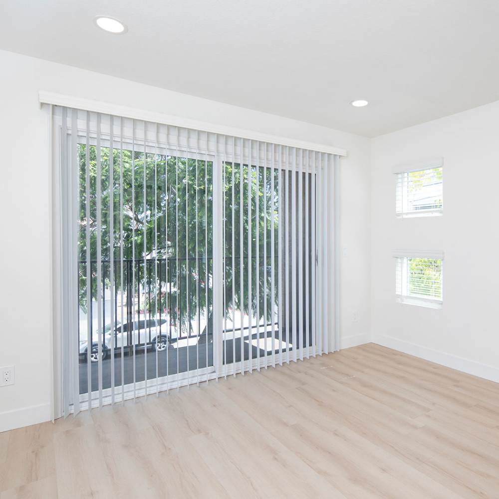 Empty living room with sliding glass door and wood-style flooring at Hillcrest Summit in San Diego, California