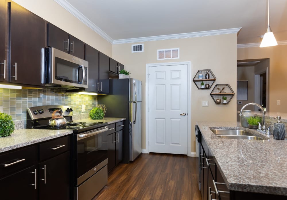 Modern kitchen with dark wood cabinets and wooden style floors at Hilltops in Conroe, Texas