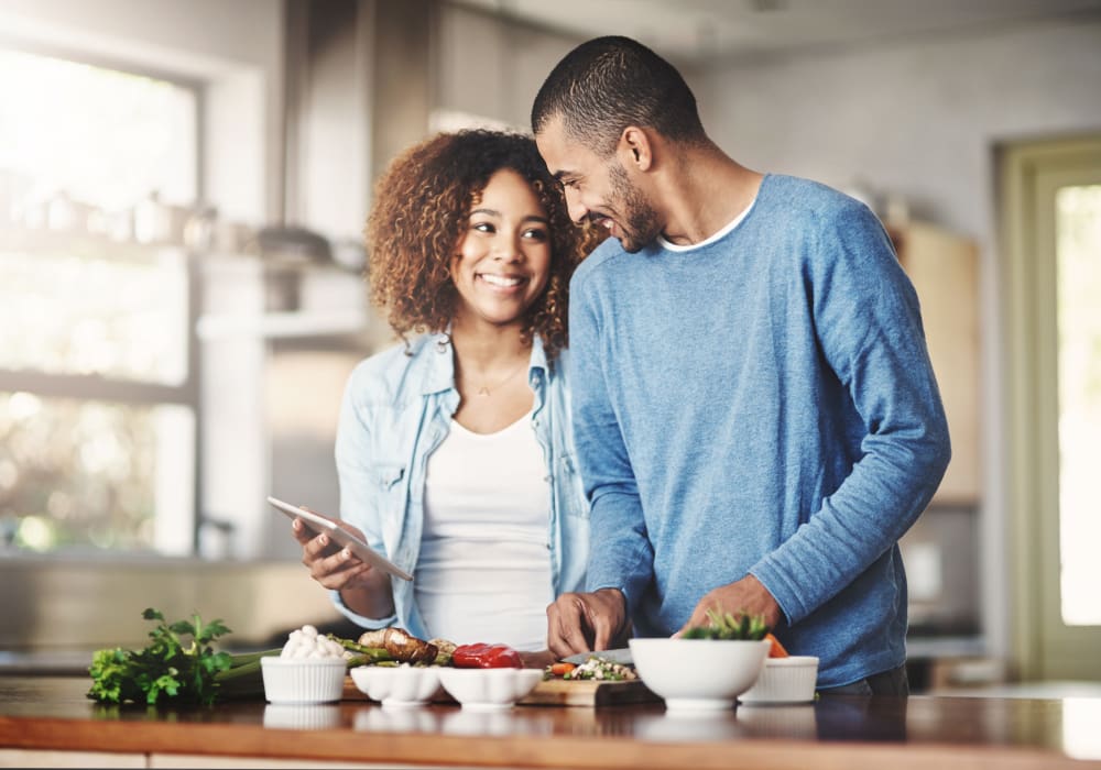 Resident couple following a recipe on a tablet as they create a fresh meal in their new home at Sofi Highlands in San Diego, California