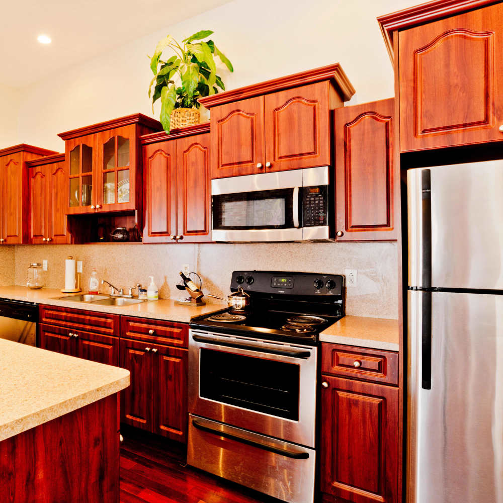 Apartment kitchen with stainless-steel refrigerator, microwave and wooden cabinets at Royal Gulf Apartments in Biloxi,Mississippi