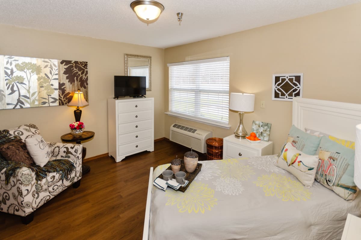 Bedroom with large bed and end table with lamp at Preston Place in Sherman, Texas