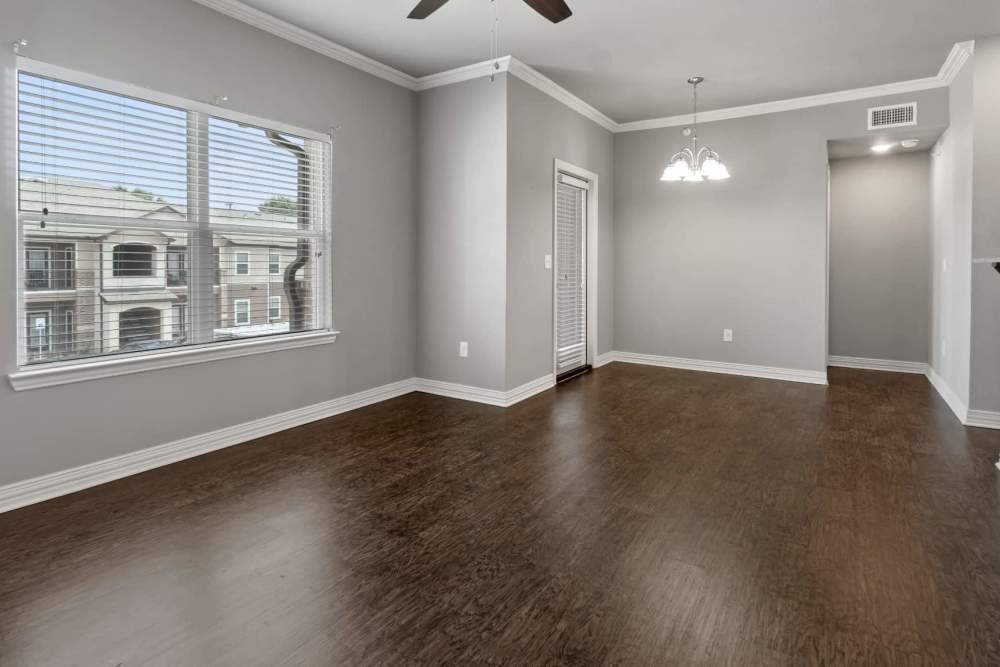 Apartment living space with wood style flooring and ceiling fan at Pine Creek in Paris, Texas