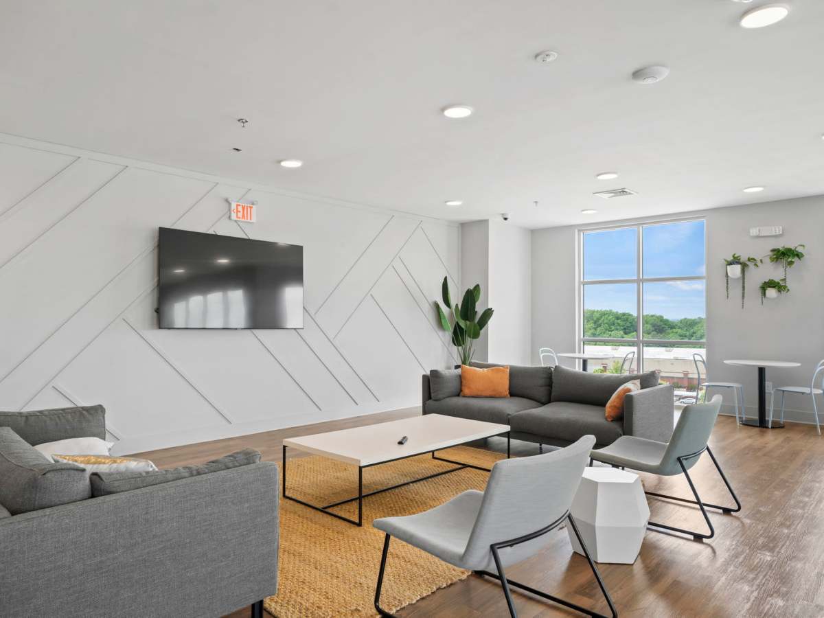 Common area with seating, flat screen television and wood-style flooring at The Rise at Regency in Henrico, Virginia