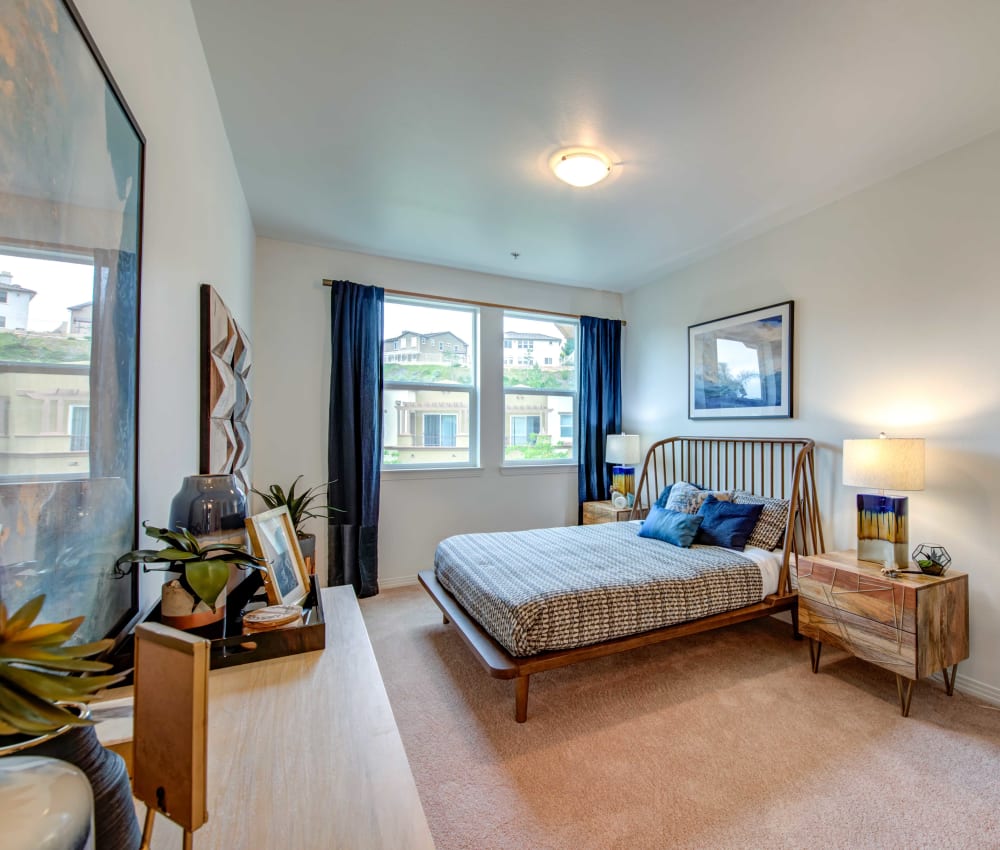 Model home's bedroom with plush carpeting and draped window at Sofi at Topanga Canyon in Chatsworth, California