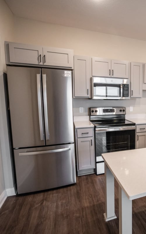 Spacious apartment kitchen with stainless steel fridge and hardwood floors at The Pillars of Hermantown in Hermantown, Minnesota