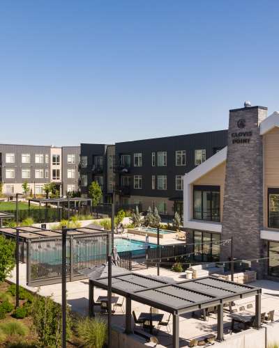 Aerial view of apartments with swimming pool, outdoor lounge area and lots of greenery at Clovis Point in Longmont, Colorado