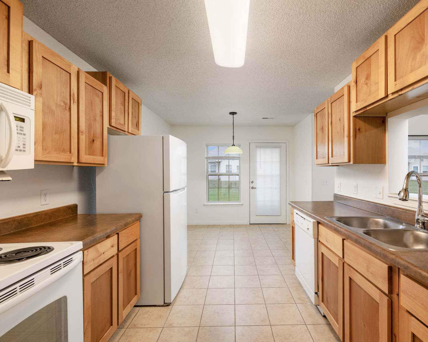 kitchen with wooden cabinets, white appliances, and double sink at Oaklawn II in Rogersville, Missouri