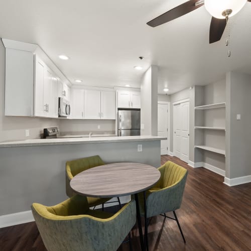 Dining room and kitchen of a model apartment home with wood-style flooring at Summerhill Terrace Apartments in San Leandro, California