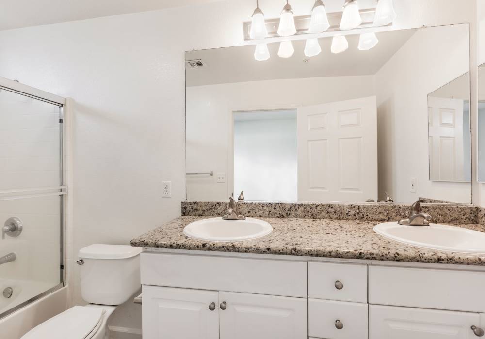 Bright bathroom with large mirror and endant lights at Park Hacienda Apartments in Pleasanton, California,