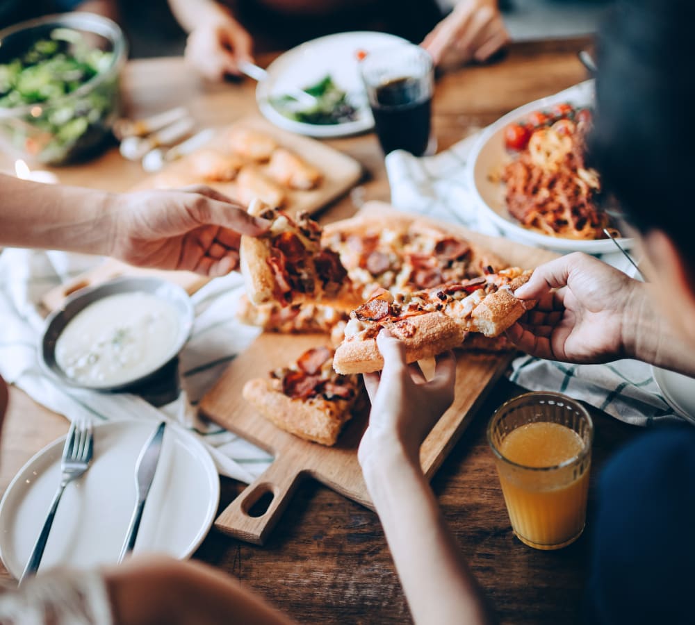 A group of friends sharing pizza near The Gables in Ridgeland, Mississippi