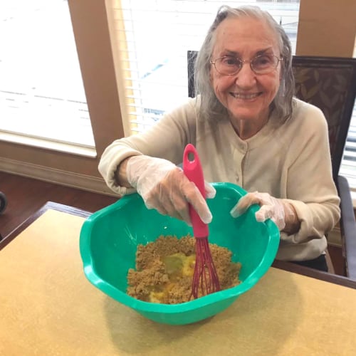 Resident mixing dough at Oxford Glen Memory Care at Grand Prairie in Grand Prairie, Texas