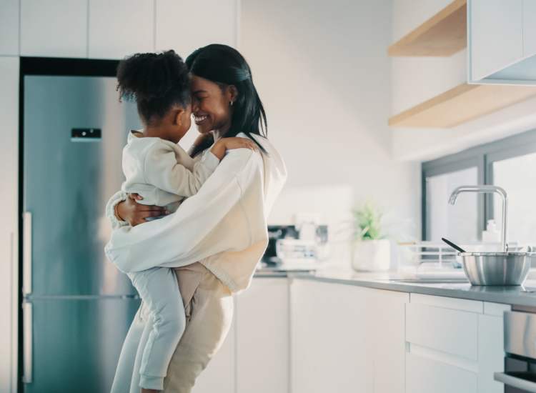 Resident hugging her child in kitchen at 71 Westland Apartments in Boston, Massachusetts