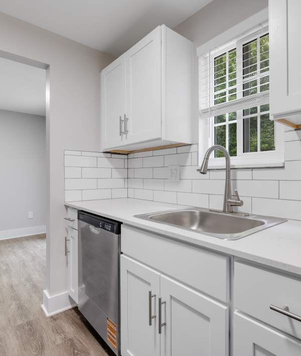 Modern kitchen with white cabinets and a dishwasher at Valley Brook Townhomes in Rochester, New York
