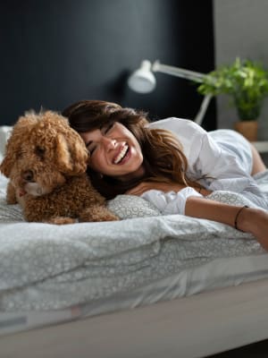 Resident smiling with dog on their bed at Anatole on MacArthur in Oklahoma City, Oklahoma