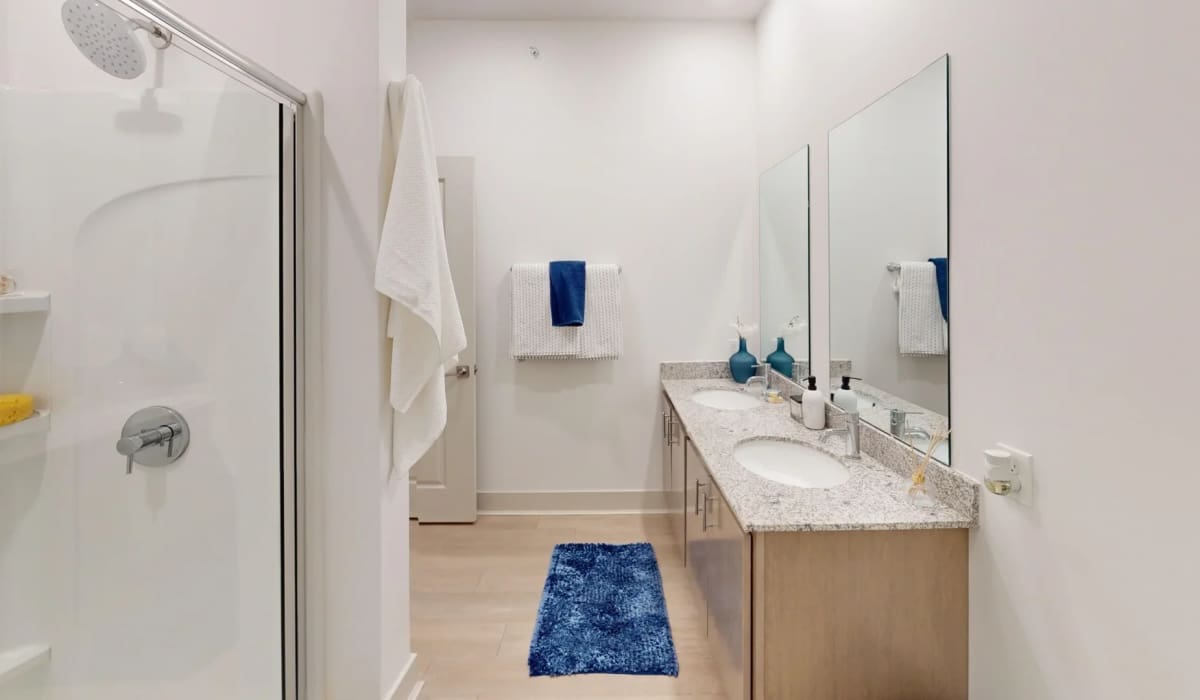 Modern bathroom in the Altitude floor plan at Elevation 800, featuring a double-sink vanity with granite countertops, large mirrors, walk-in shower, and contemporary finishes.