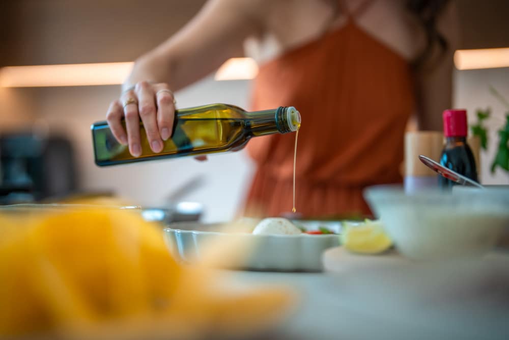 Woman cooking in modern kitchen with fresh ingredients at Apperson Way Apartments in Kokomo, Indiana