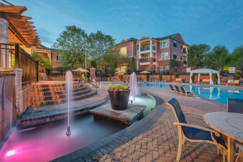 Resort style pool with lounge chairs and a pretty fountain on the side at The Vive in Kannapolis, North Carolina