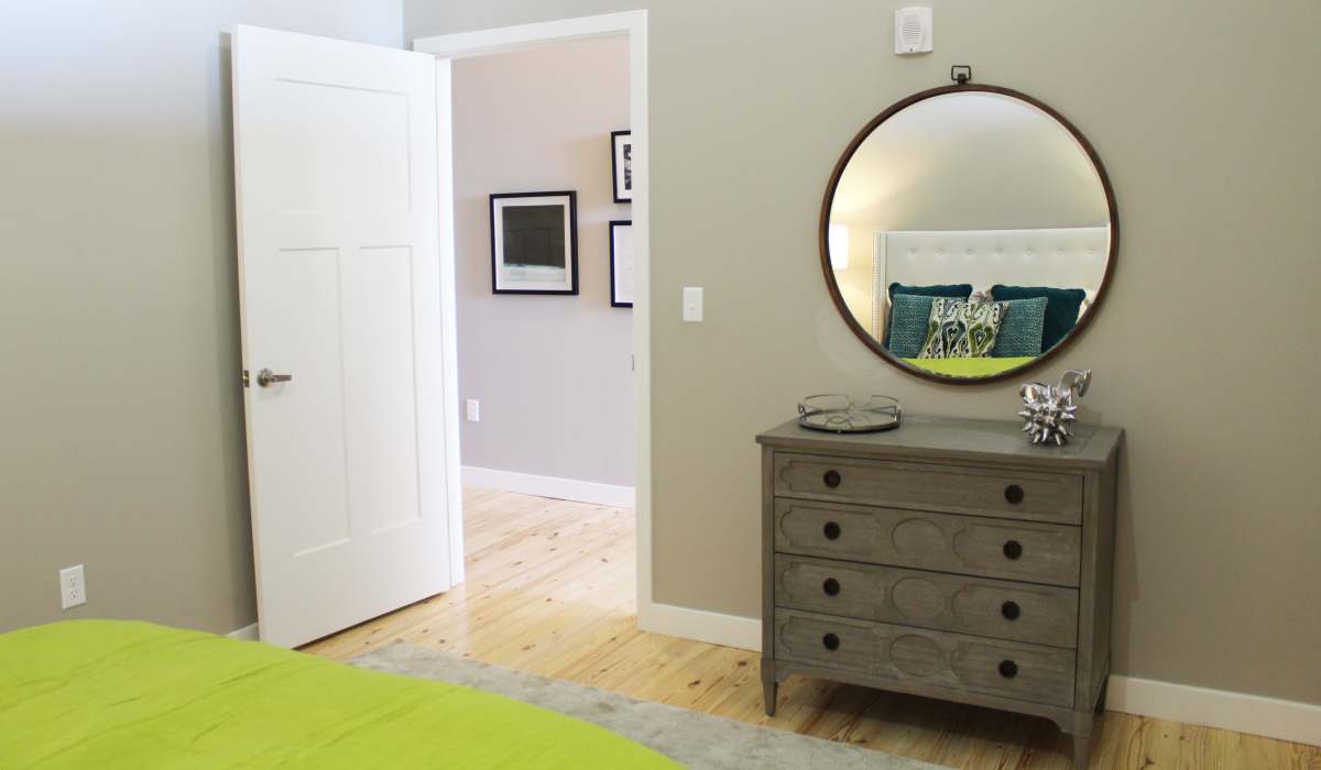 New round mirror above a dresser with decor at Commonwealth Landing Lofts in Fall River, Massachusetts