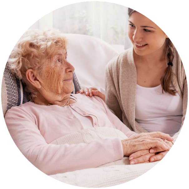 Resident laying in bed while a younger family member talks to them at Ebenezer Senior Living