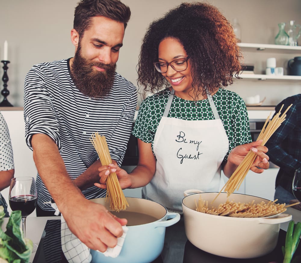 Couple cooking for friends in their fully-equipped kitchen at Haven Apartment Homes in Kent, Washington