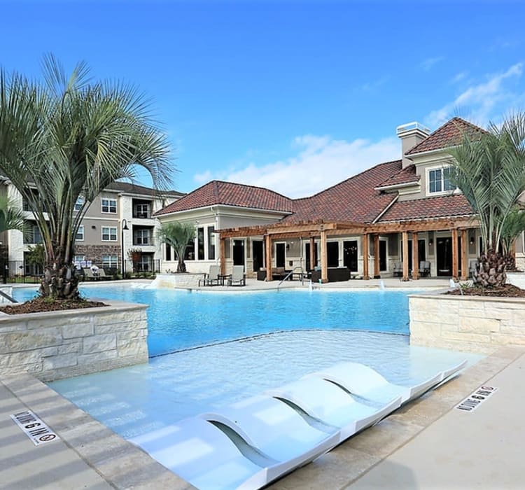 Resorty-style swimming pool with shallow water chairs at Trails at Lake Houston in Houston, Texas