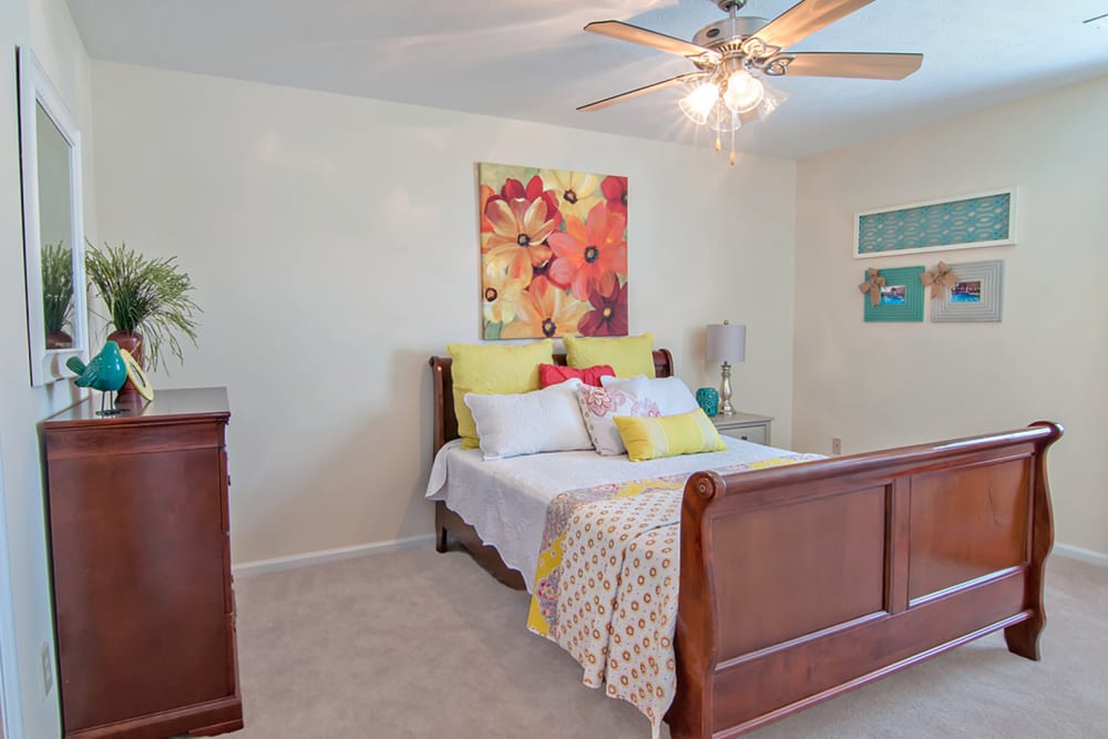 Colorful bedroom with bed, dresser, and ceiling fan at Greenleaf Apartments in Phenix City, Alabama