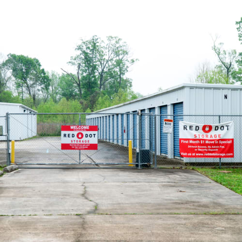 Outdoor storage units with blue doors behind a security fence at Red Dot Storage in Baker, Louisiana