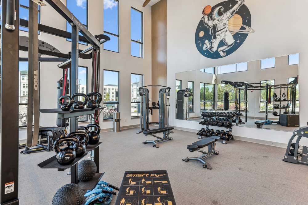 Fully-equipped gym with treadmills, flat-screen TVs, and ceiling fans at Mosby Bridge Street in Huntsville, Alabama