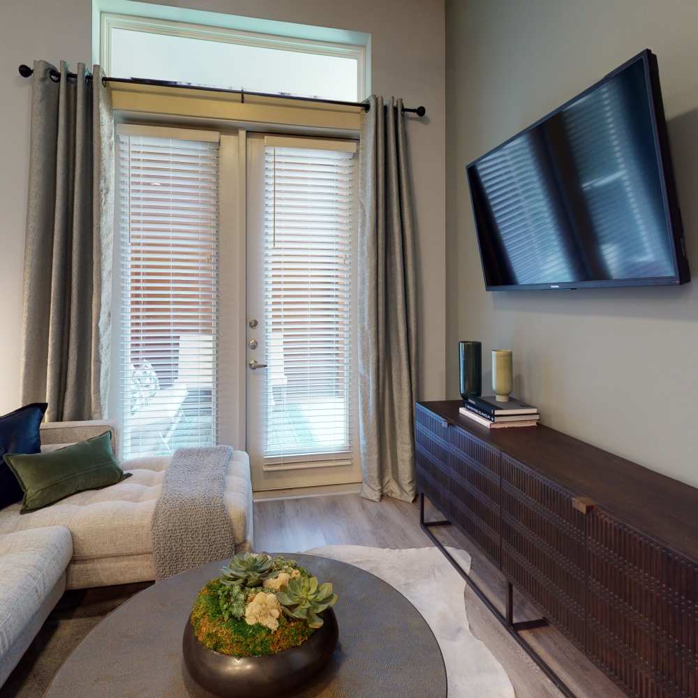 Living room with a couch and entry to patio access at Cornell Midtown in Dallas, Texas