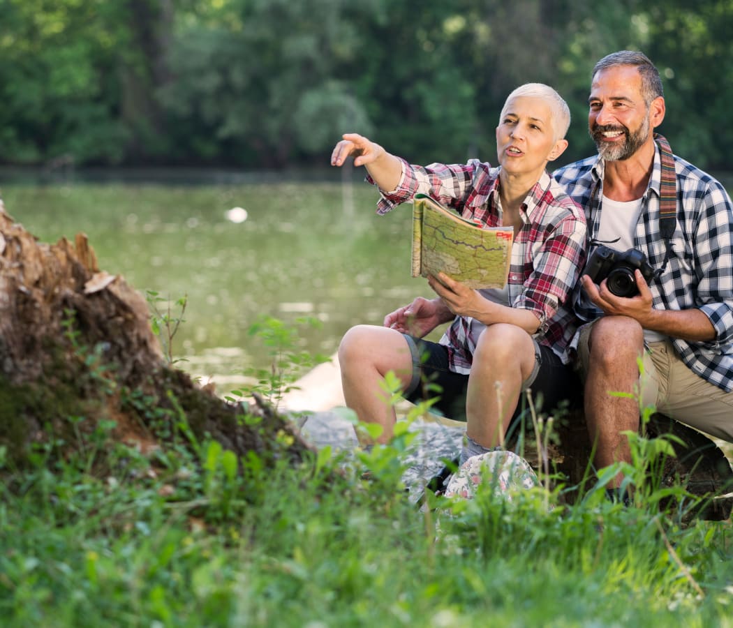 A man and a woman following directions from a map next to the lake at Orchard Hills Senior Apartments in Thornton, Colorado
