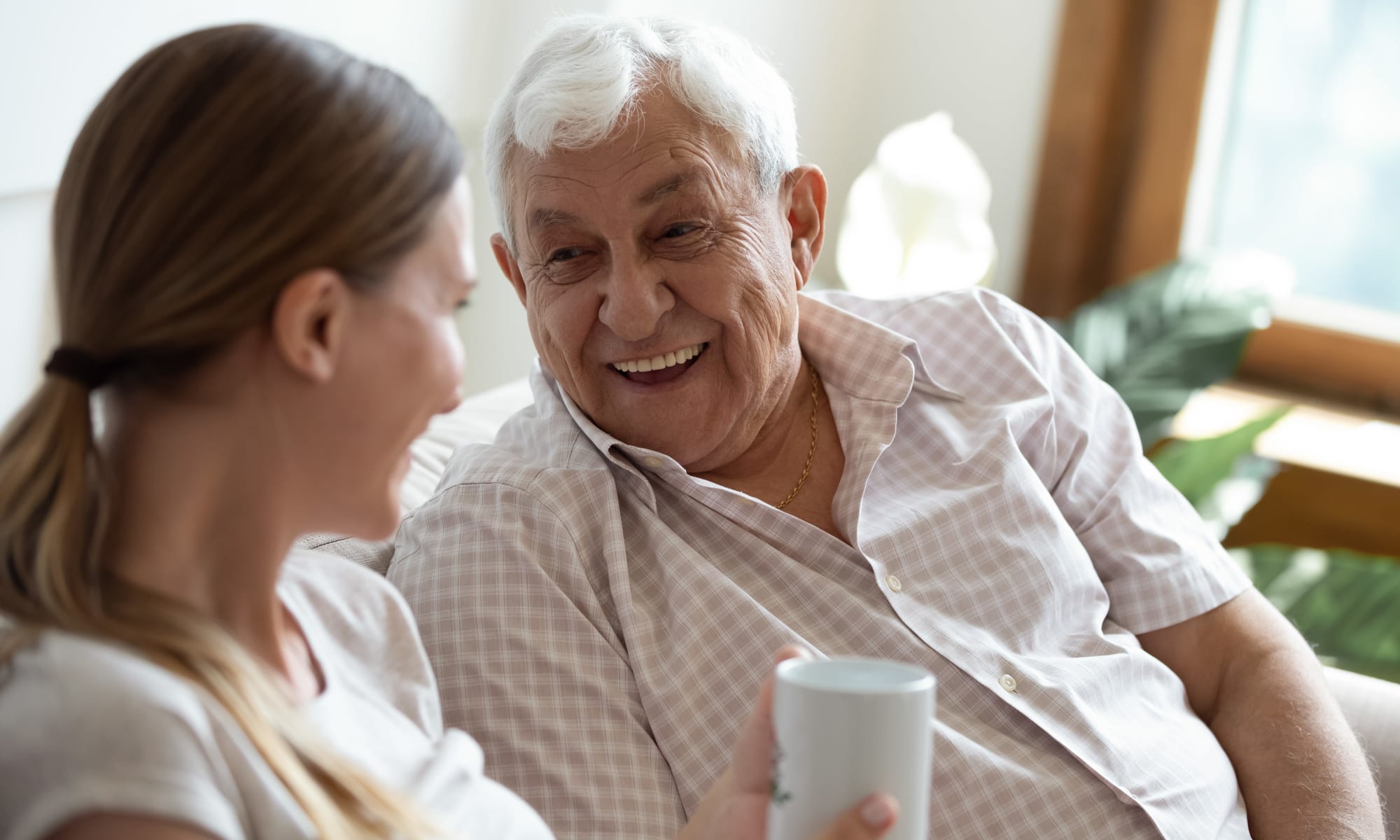 Grandfather having a cup of tea with his granddaughter at Broadwell Senior Living in Plymouth, Minnesota