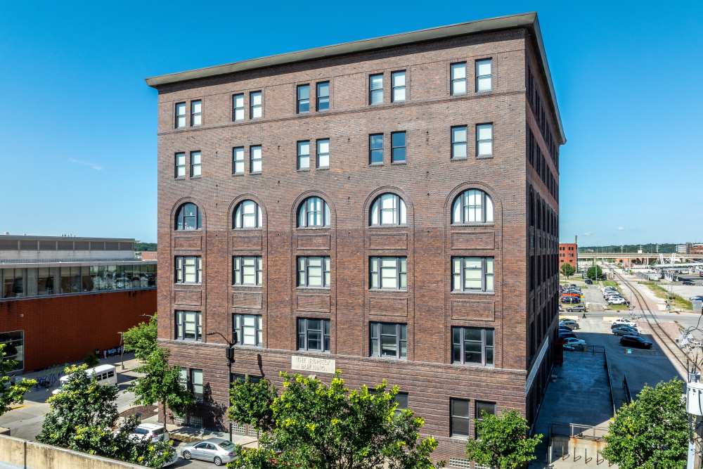 Brick building with arched windows and greenery at Rumely Lofts in Des Moines, Iowa