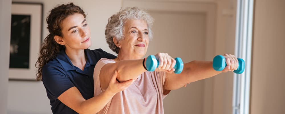 A staff member assisting a resident in an exercise at Ridgeline Management Company in Rockwall, Texas