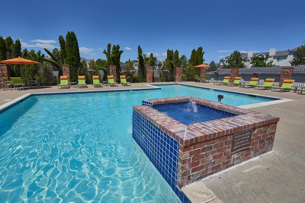 Sparkling pool with a fountain and lounge area at Villas at Homestead Apartments in Englewood, Colorado