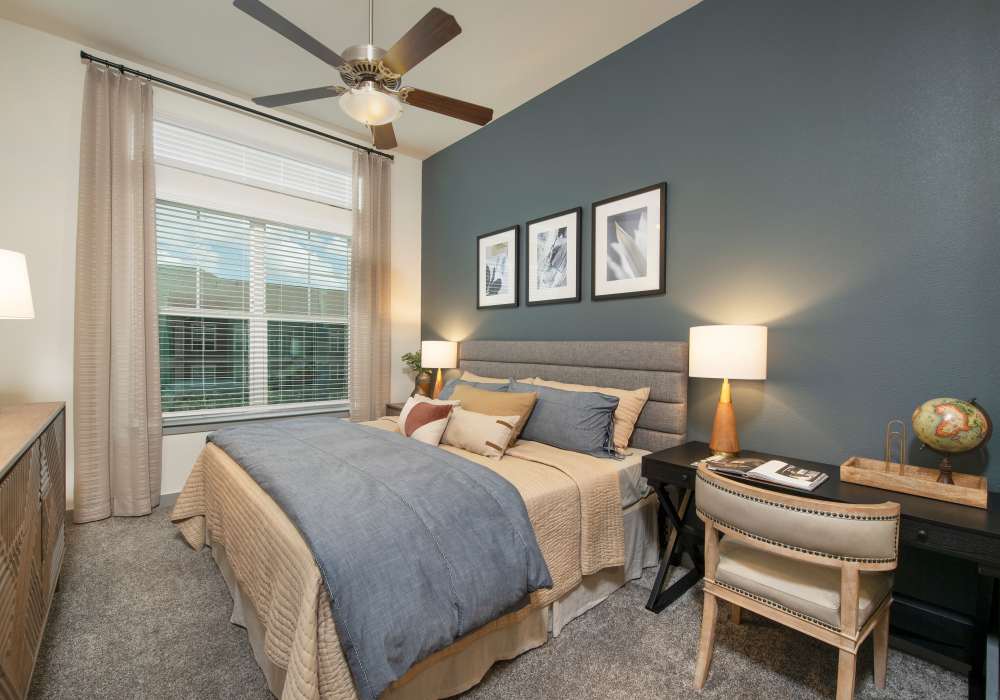 Comfortable bedroom with king size bed, side table lamp and study desk at Orleans at Fannin Station in Houston, Texas