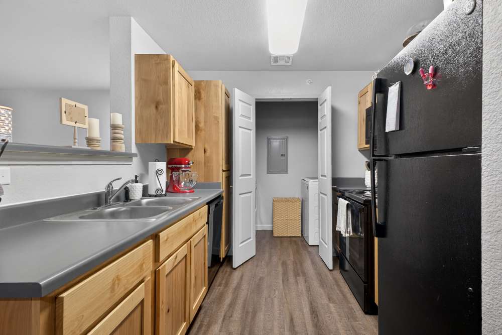 Charming modern kitchen with sleek black appliances and warm wooden cabinetry at Lakewood Crossing in Granbury, Texas.