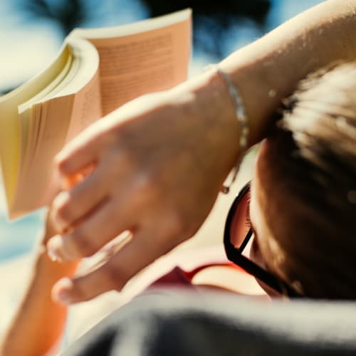 Resident reading in a sunny poolside lounge chair at Solaire 8200 Dixon in Silver Spring, Maryland