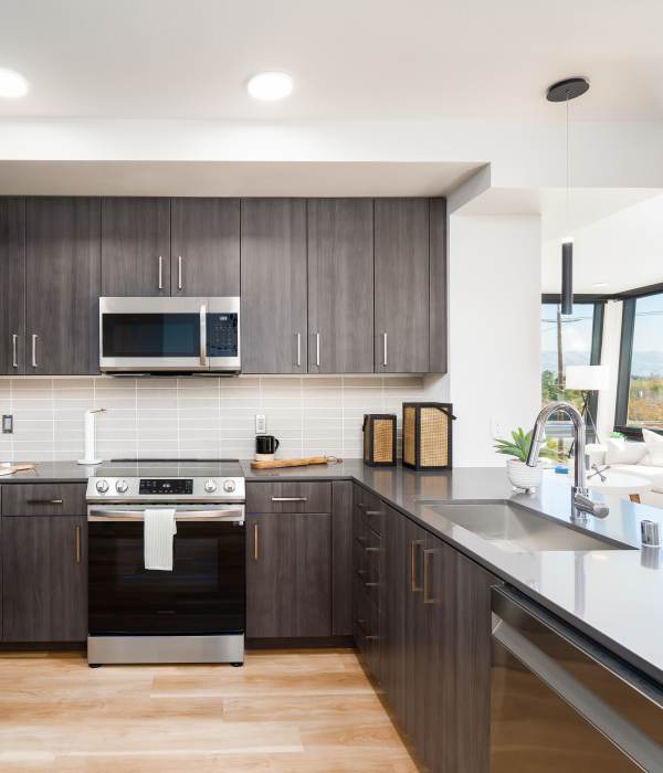 Modern kitchen with stainless steel appliances, granite countertops, and wood-style flooring at Exhibit at J Town in San Jose, California