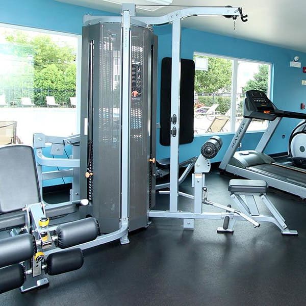 Fully-Equipped fitness center with large windows and view of pool at West Line Apartments in Hanover Park, Illinois