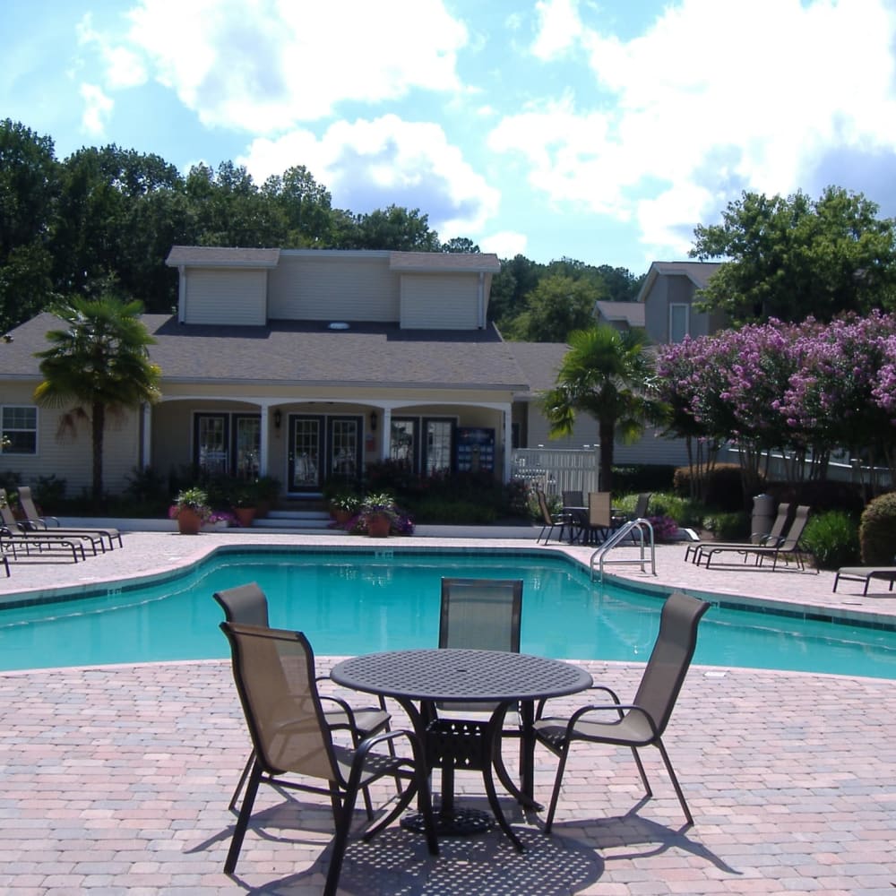 Swimming pool surrounded by lounge chairs and flowering trees at Park at Northside Apartments & Townhomes in Macon, Georgia