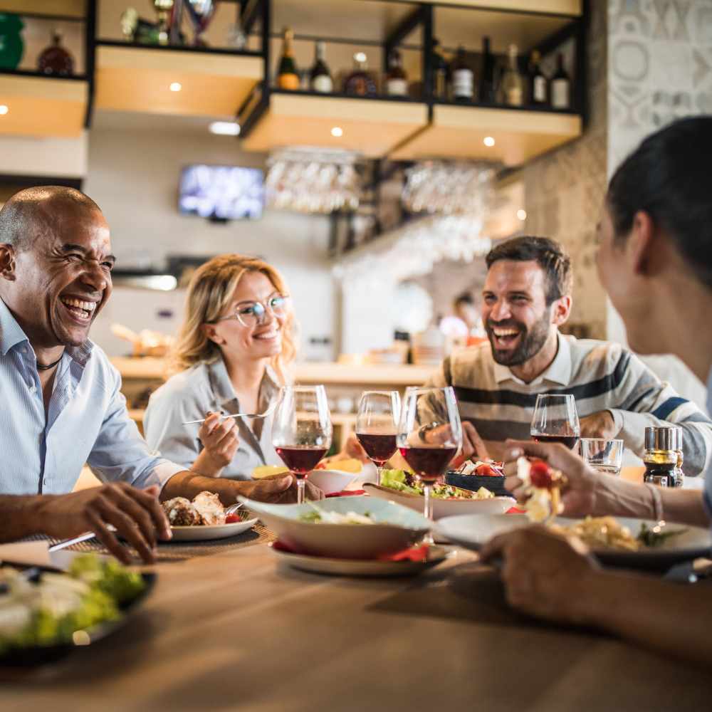 Resident friends sharing a laugh over a meal at restaurant near Saratoga Place Apartments in Suffolk, Virginia