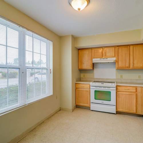 Kitchen with white appliances and wooden cabinetry at Jenny Greene in Hardeeville, South Carolina