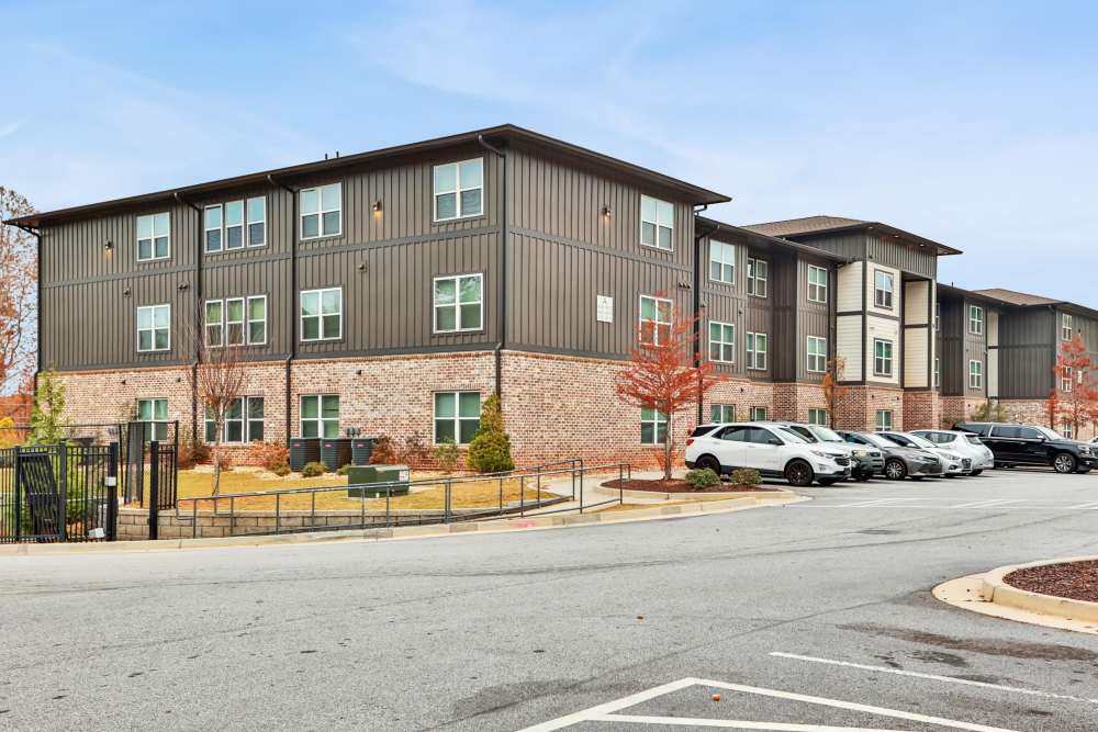 An exterior view of the apartment building with car parking at Flats at Mount Zion in Stockbridge, Georgia