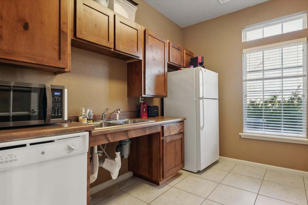 Charming kitchen with warm wooden cabinetry and bright natural light at Covington Woods Apartments in Lansing, Kansas.