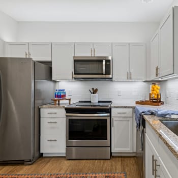 Upgraded stainless steel appliances and white cabinets in an apartment kitchen at Cypress Creek at Hazelwood in Princeton, Texas